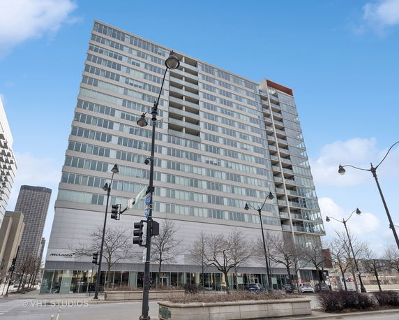 Front view of a multi-story building with glass windows and balconies.
