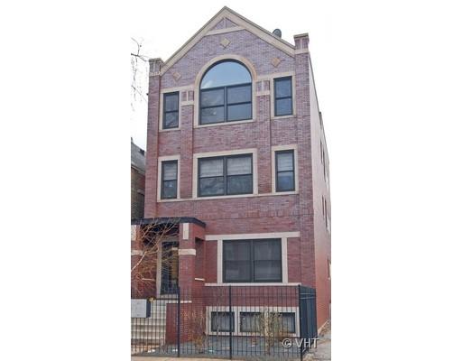 Front view of a multi-story brick building with a prominent arched window and a gated entrance.