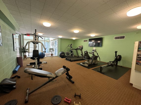 Indoor gym area with exercise equipment including treadmills, weight machines, and exercise bikes.