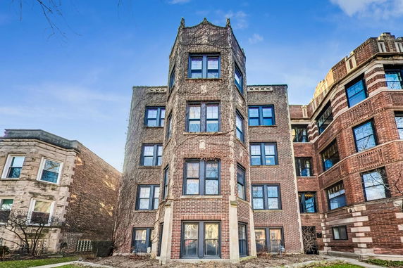 Front view of a multi-story brick building with multiple windows and a distinctive architectural design.