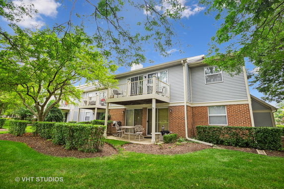 Rear view of a two-story house with balconies and a patio area.