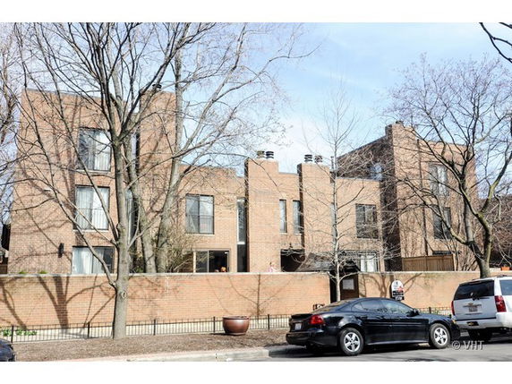 Front view of a multi-story brick building with large windows and a fenced entrance.