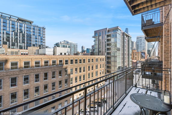 View from a balcony showing multiple buildings in a cityscape, including modern high-rises and a brick building.