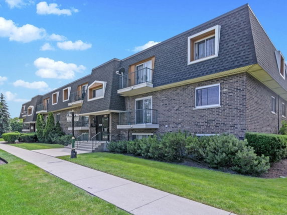 Front view of a two-story apartment building with brick facade and balconies.