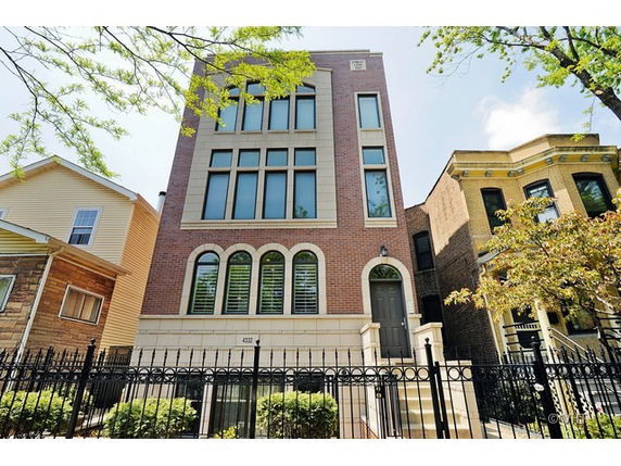 Front view of a multi-story house with large windows and brick facade.