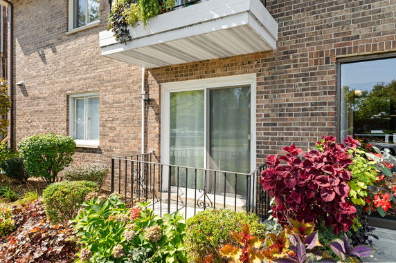 Front view of a brick building with a small balcony and sliding glass door.