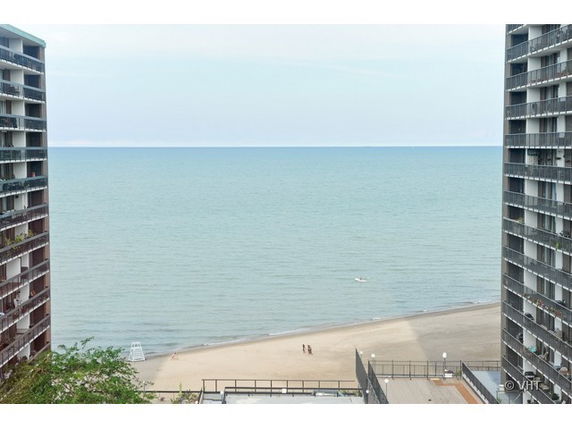 Panoramic view of a beach and ocean between two high-rise buildings.