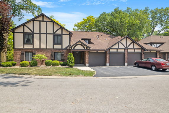 Front view of a two-story house with a garage and Tudor-style design.