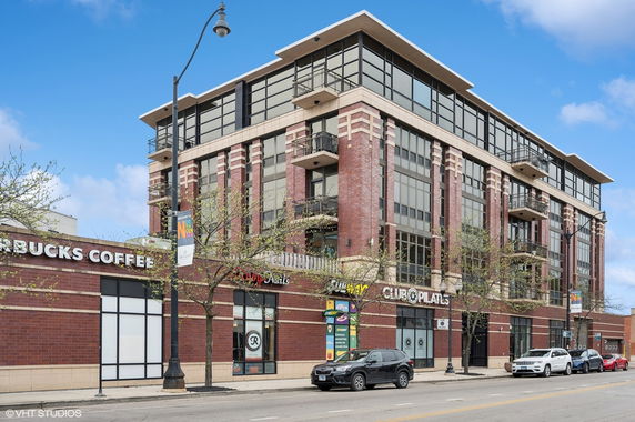 Front view of a multi-story commercial building with large windows and retail shops on the ground level.