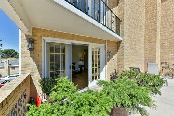 Front view of a building with a small patio and sliding glass doors.
