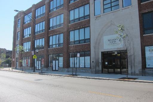 Front view of a multi-story brick building with large windows.