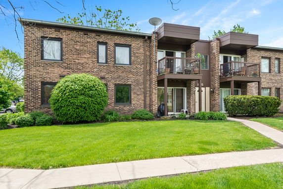 Front view of a two-story brick apartment building with balconies.