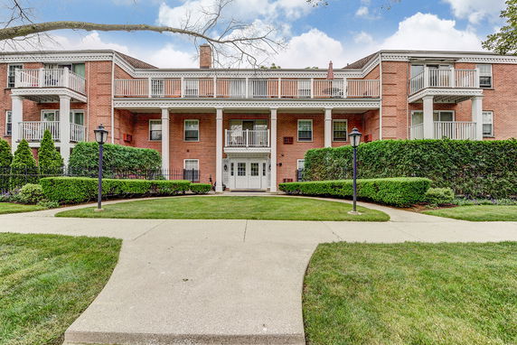 Front view of a two-story brick building with white columns and balconies.