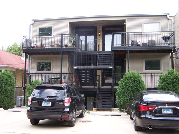 Front view of a two-story building with balconies and a central staircase.