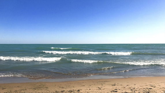 Panoramic view of the ocean with waves and blue sky.