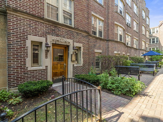 Front view of a brick apartment building with a landscaped entrance.