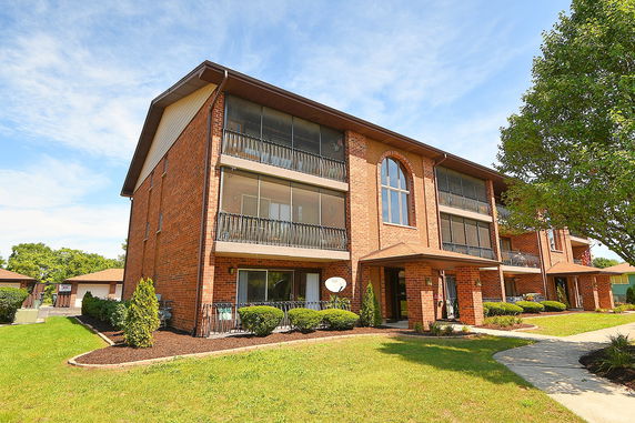 Front view of a multi-story brick building with balconies and large windows.
