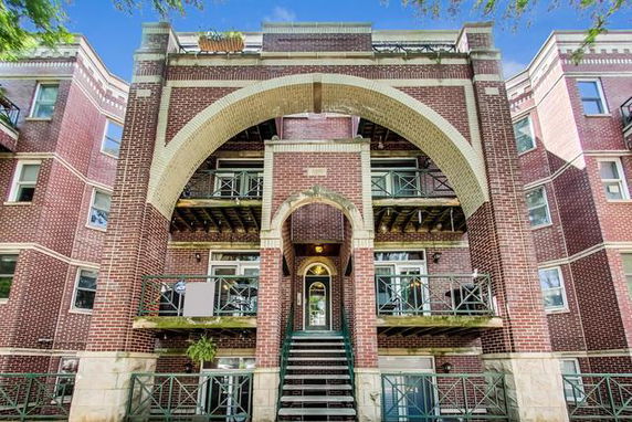 Front view of a multi-story brick building with arched entrance.