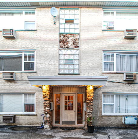 Front view of a multi-story brick building with multiple windows and air conditioning units.