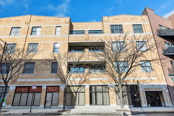 Front view of a multi-story brick building with large windows.