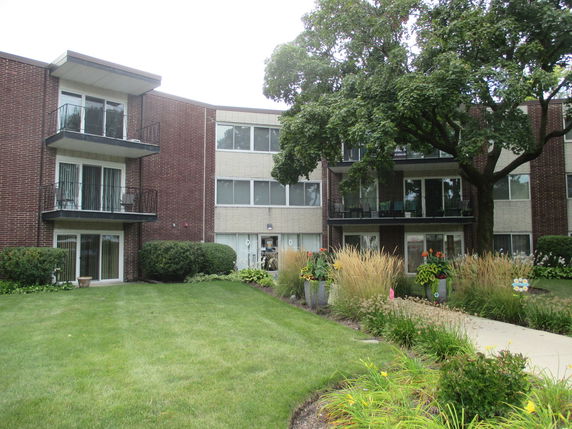 Front view of a multi-story brick apartment building with balconies.