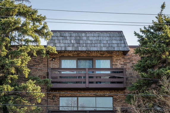 Front view of a building with a balcony and brick exterior.