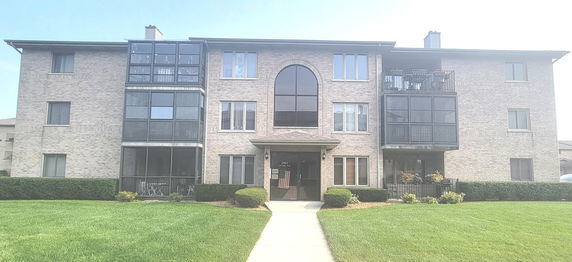 Front view of a multi-story brick residential building with large windows and balconies.