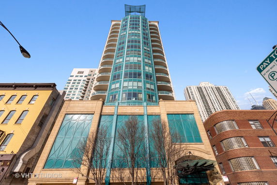 Front view of a tall, modern building with a blue and tan facade featuring round balconies.