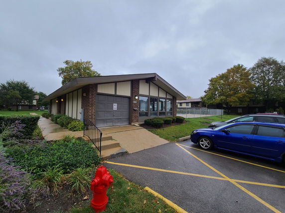 Front view of a single-story building with a large window facade and a side entrance.