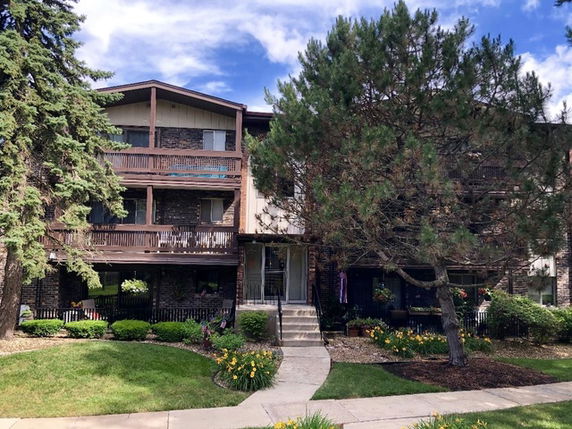 Front view of a multi-story residential building with balconies and brick facade.