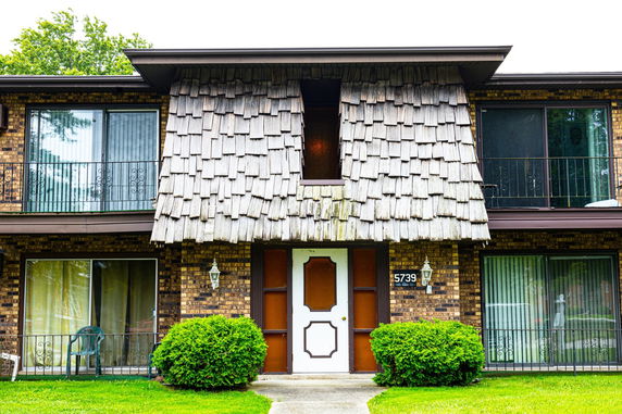 Front view of a two-story house with a gabled roof and brick exterior.