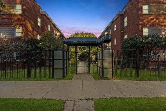 Front view of a brick apartment building with a gated entrance.