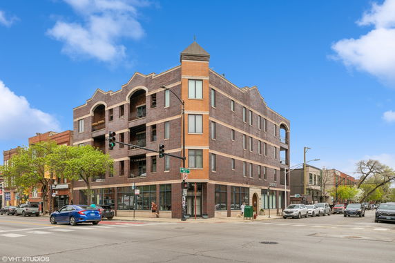 Front view of a multi-story brick building on a street corner.