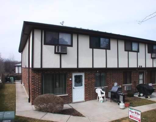 Front view of a two-story brick building with white paneled upper sections and multiple windows.