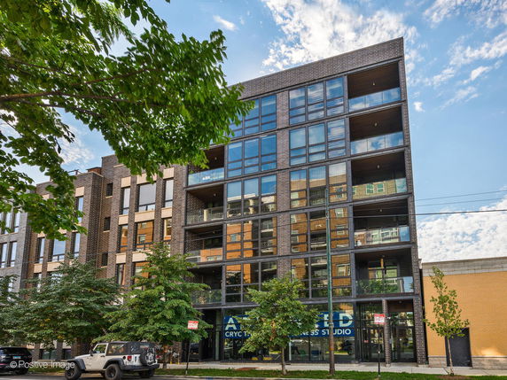 Front view of a modern multi-story apartment building with large windows and balconies.