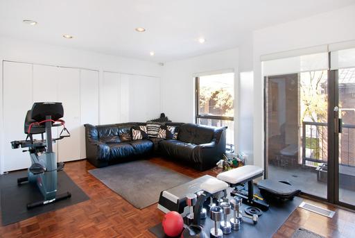 Room with exercise equipment and a black leather couch