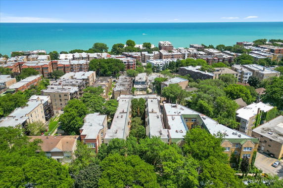Panoramic view of buildings and trees with a large body of water in the background.