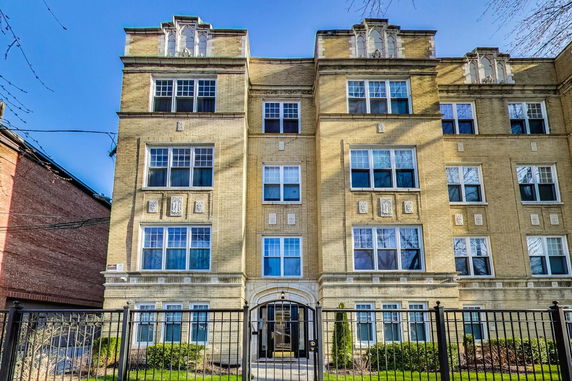 Front view of a multi-story brick building with multiple windows and decorative elements.