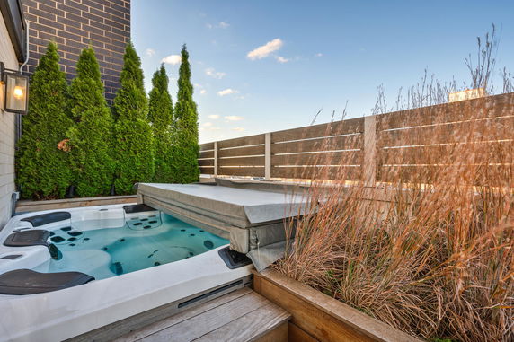 Rooftop area with a hot tub and greenery surrounding it.