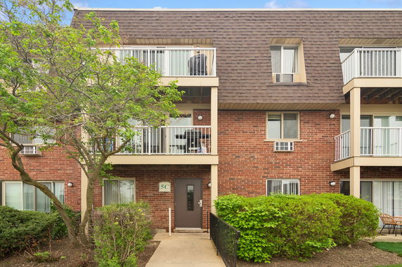 Front view of a three-story brick building with balconies.