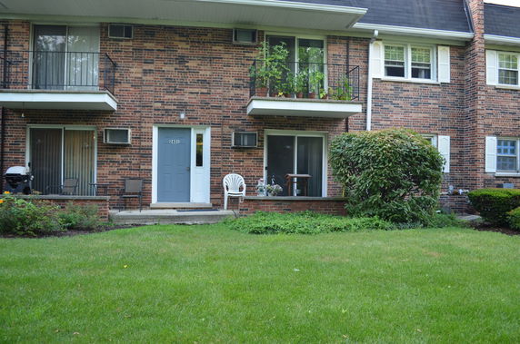 Front view of a two-story brick house with balconies and blue door.