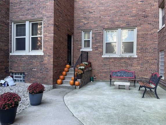 Front view of a brick building with steps decorated with pumpkins and outdoor seating.