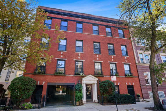 Front view of a four-story brick building with multiple windows and a gated entrance.