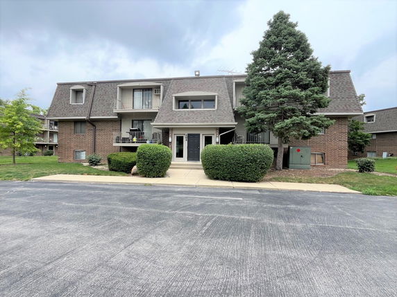 Front view of a two-story residential building with balconies and a sloped roof.