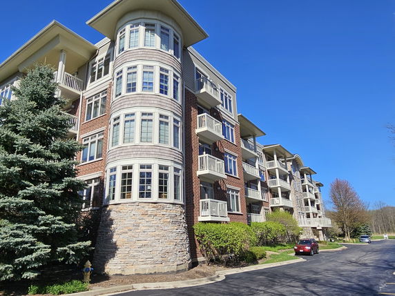 Front view of a multi-story building with brick and stone facade, featuring balconies and large windows.