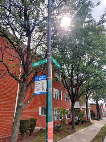 Front view of a brick apartment building adjacent to a sidewalk.
