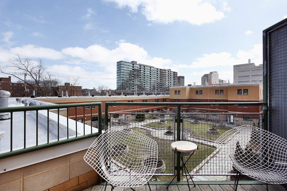 Panoramic view from a rooftop terrace with seating overlooking a residential area.