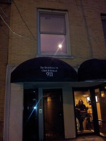 Front view of a building with an entrance canopy labeled 'The Residence At Clark & School 911'.