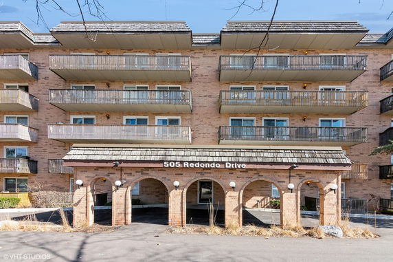 Front view of a multi-story brick apartment building with balconies.