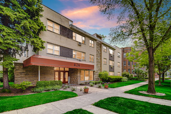 Front view of a multi-story residential building with a brick facade and entrance canopy.